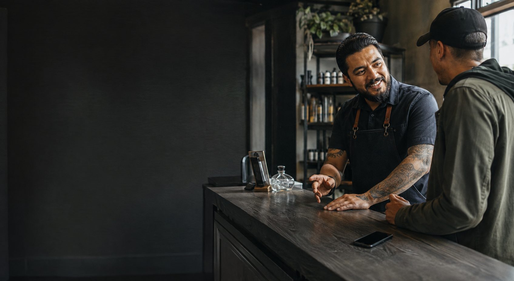 Owner-operator speaking with a customer at the front counter while the booking system runs in the background.