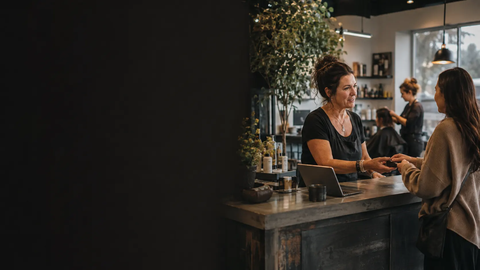 Salon owner serving a customer while the existing operation continues behind them